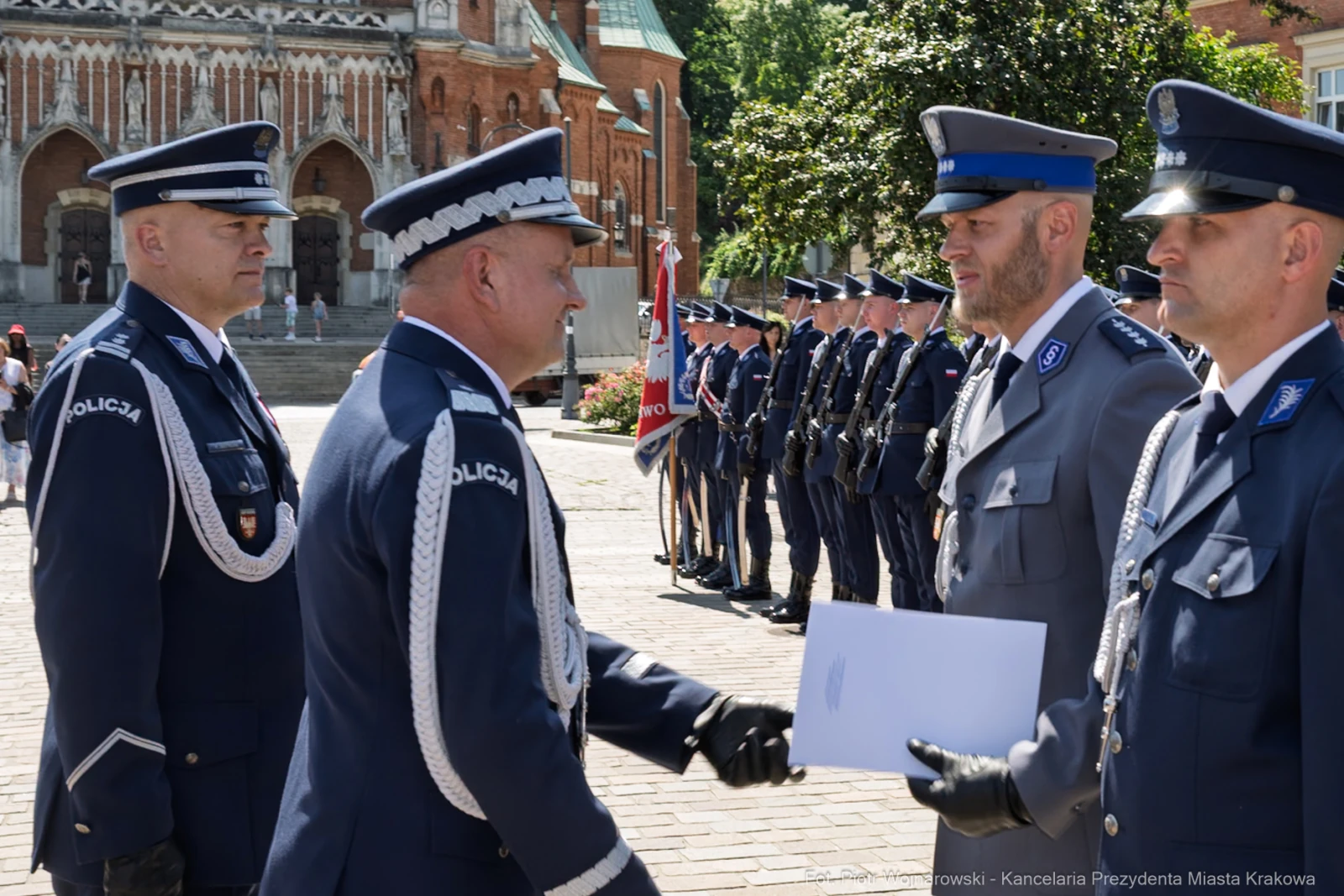 Ceremonia wręczenia odznaczeń policjantom w otoczeniu mundurowych i budynków historycznych.  Autor: Piotr Wojnarowski