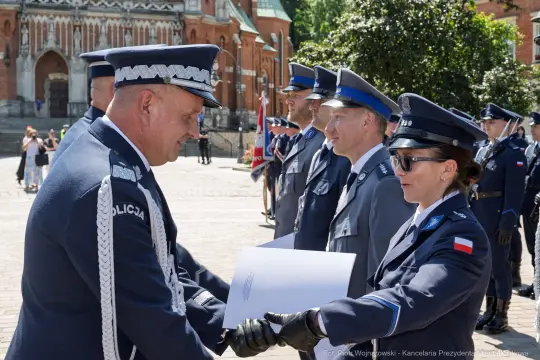 Ceremonia wręczenia odznaczeń policjantom w mundurach na tle zabytkowej architektury.