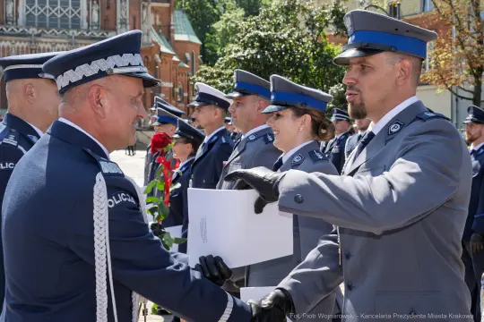 Ceremonia wręczenia odznaczeń policjantom w mundurach na tle zabytkowej architektury.
