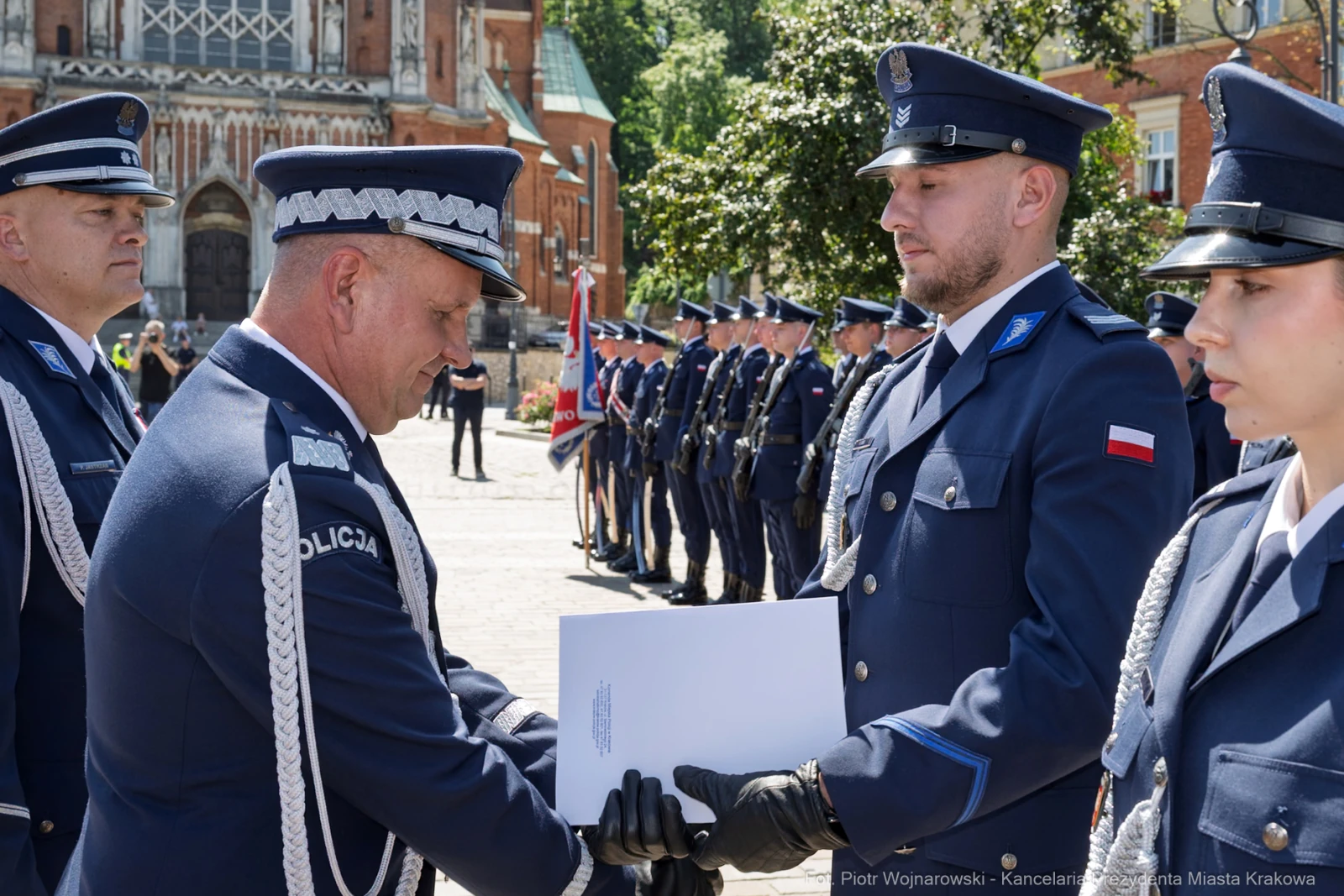 Ceremonia wręczenia odznaczeń policjantom w mundurach na tle zabytkowego budynku.  Autor: Piotr Wojnarowski