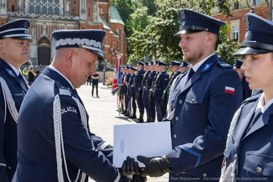 Ceremonia wręczenia odznaczeń policjantom w mundurach na tle zabytkowego budynku.