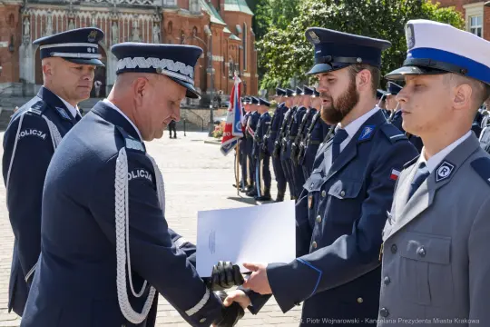 Ceremonia wręczenia odznaczeń policjantom w mundurach na tle budynków.