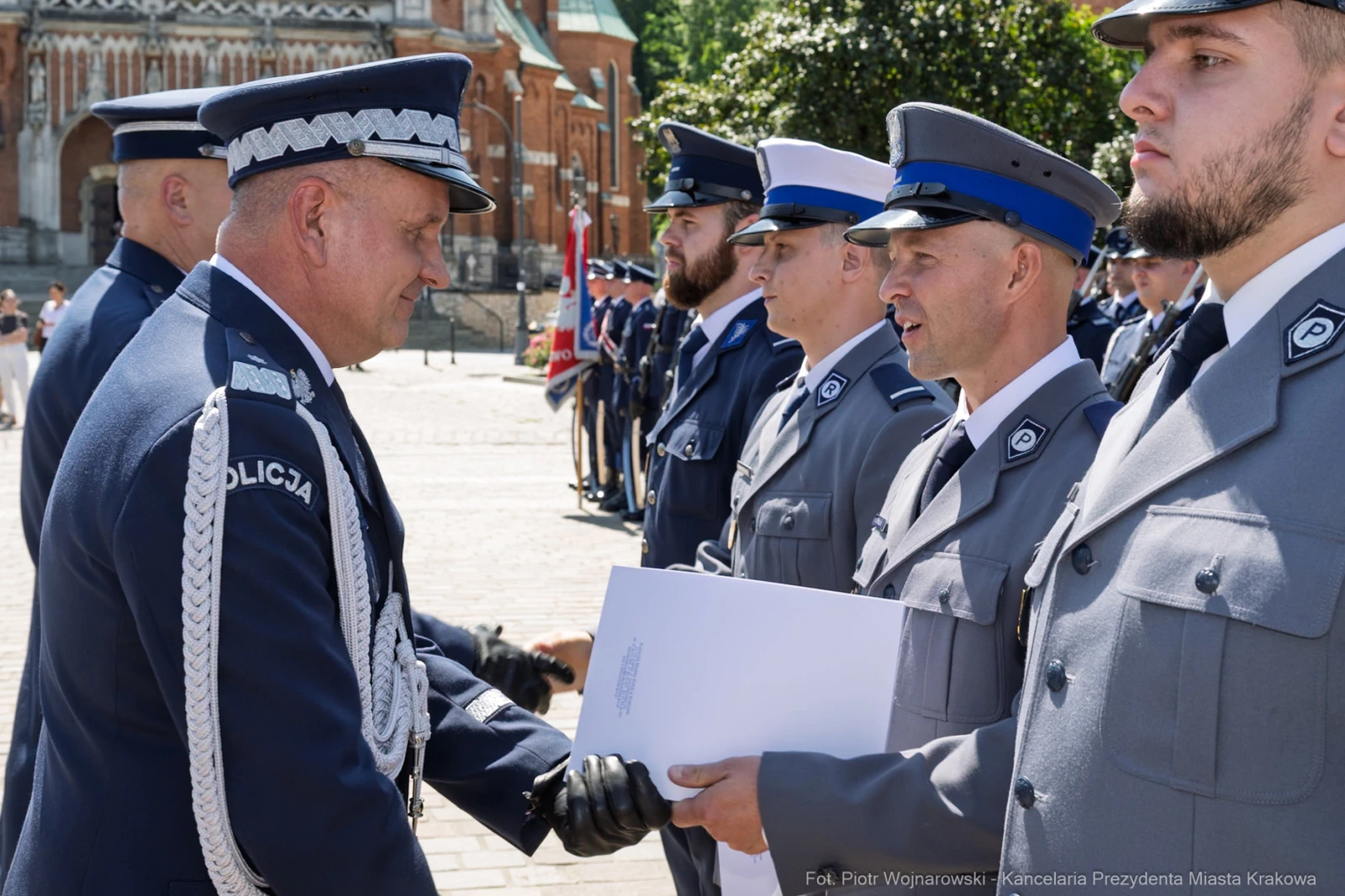 Ceremonia wręczenia odznaczeń policjantom w mundurach na tle zabytkowej architektury.  Autor: Piotr Wojnarowski