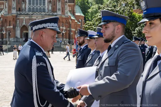 Ceremonia wręczenia odznaczeń policjantom na tle budynku w Krakowie.
