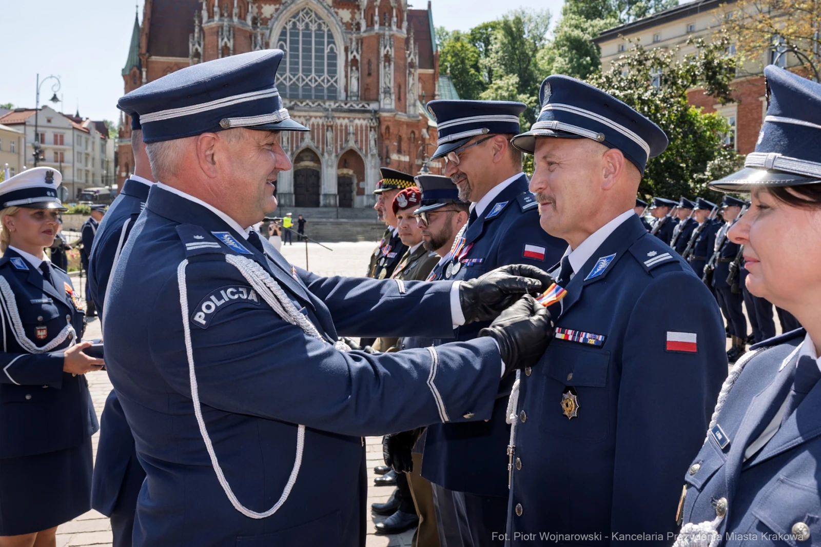 Ceremonia wręczenia odznaczeń policjantom w tle zabytkowy budynek.  Autor: Piotr Wojnarowski