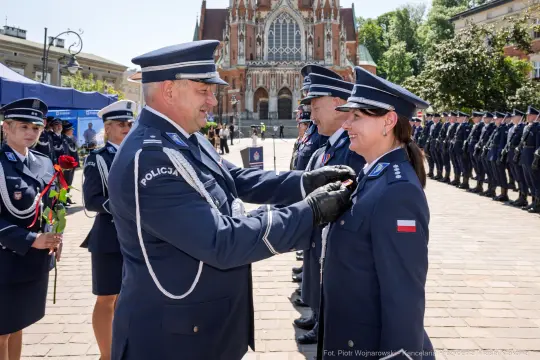 Ceremonia wręczenia odznaczeń policjantom na tle zabytkowego budynku.