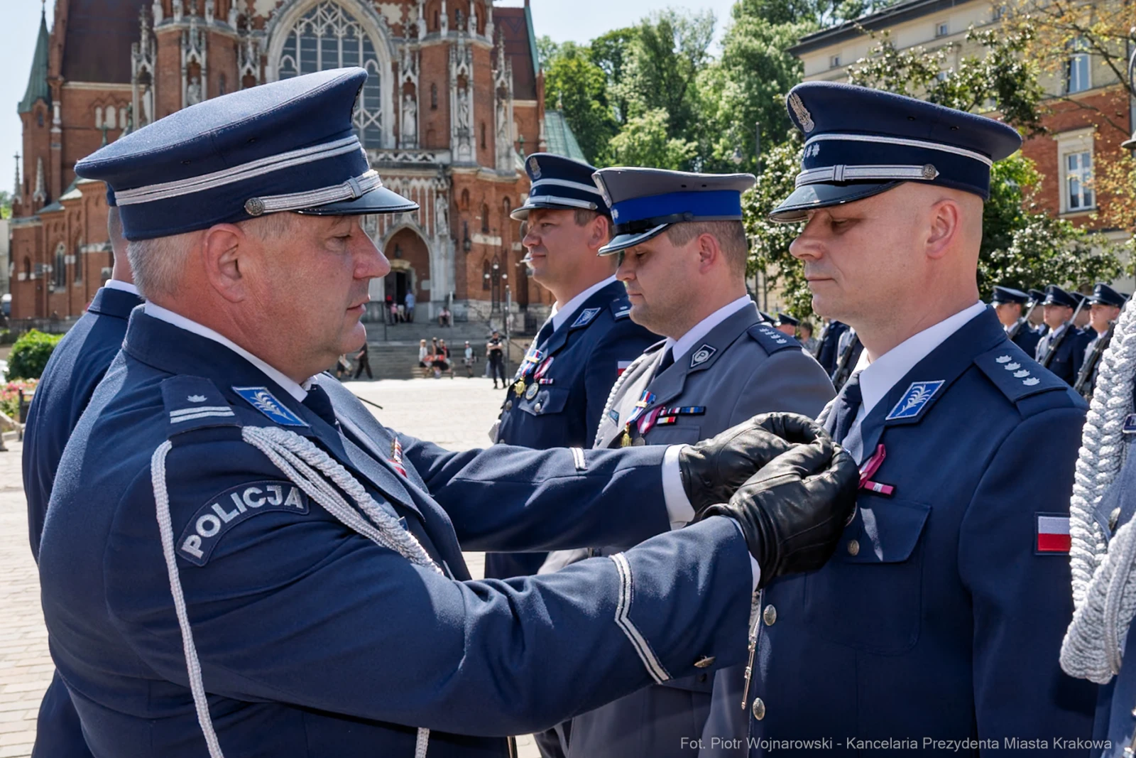 Ceremonia wręczenia odznaczeń policjantom w otoczeniu budynków historycznych.  Autor: Piotr Wojnarowski