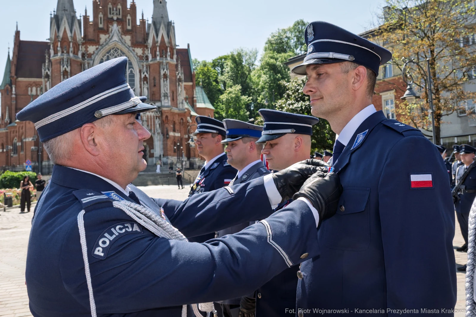 Ceremonia wręczenia odznaczeń policjantom w tle budowli sakralnej.  Autor: Piotr Wojnarowski