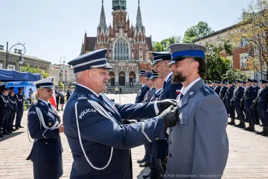 Ceremonia wręczenia odznaczeń policyjnych na tle zabytkowego budynku.