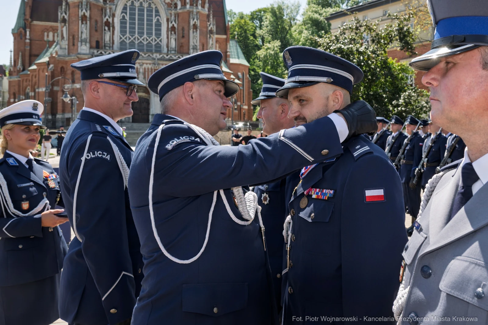 Ceremonia wręczenia odznaczeń policjantom w mundurach, w tle budynek.  Autor: Piotr Wojnarowski