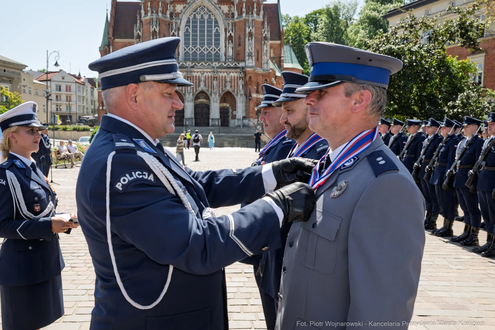 Ceremonia wręczenia medali policjantom na tle zabytkowego budynku.  Autor: Piotr Wojnarowski