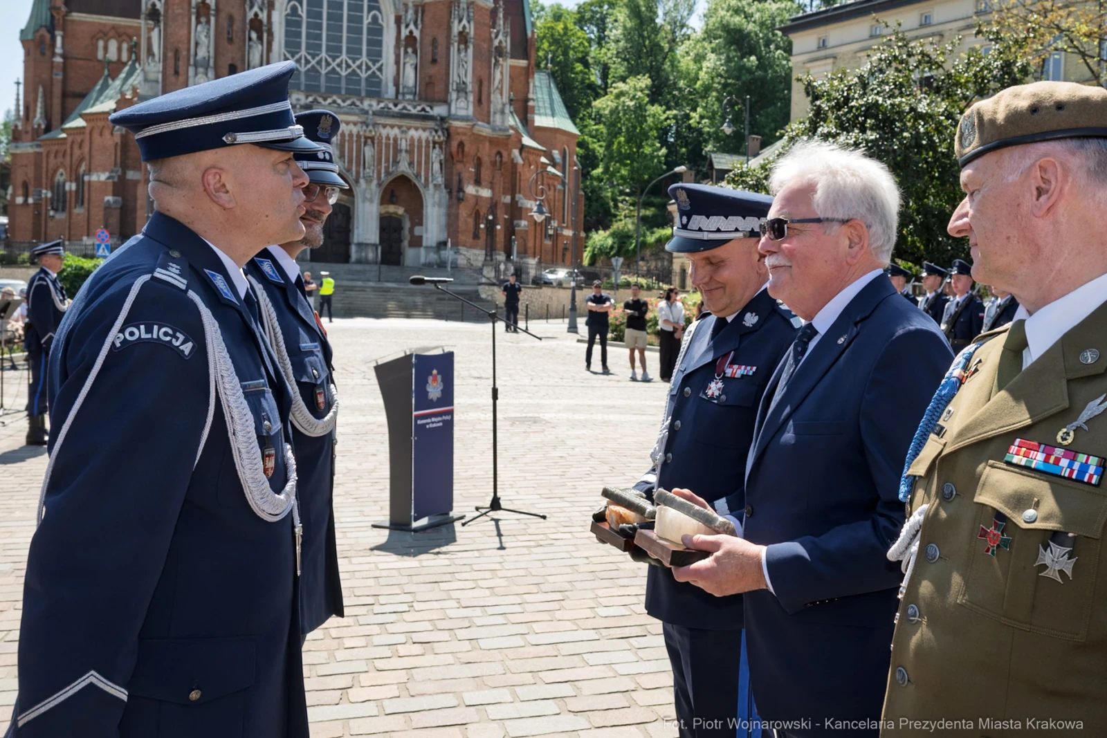 Ceremonia wręczenia odznaczeń w plenerze, uczestnicy w mundurach, budynek w tle.  Autor: Piotr Wojnarowski
