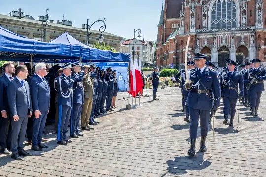Uroczystość wojskowa z udziałem żołnierzy i oficjeli, flagi Polski w tle.