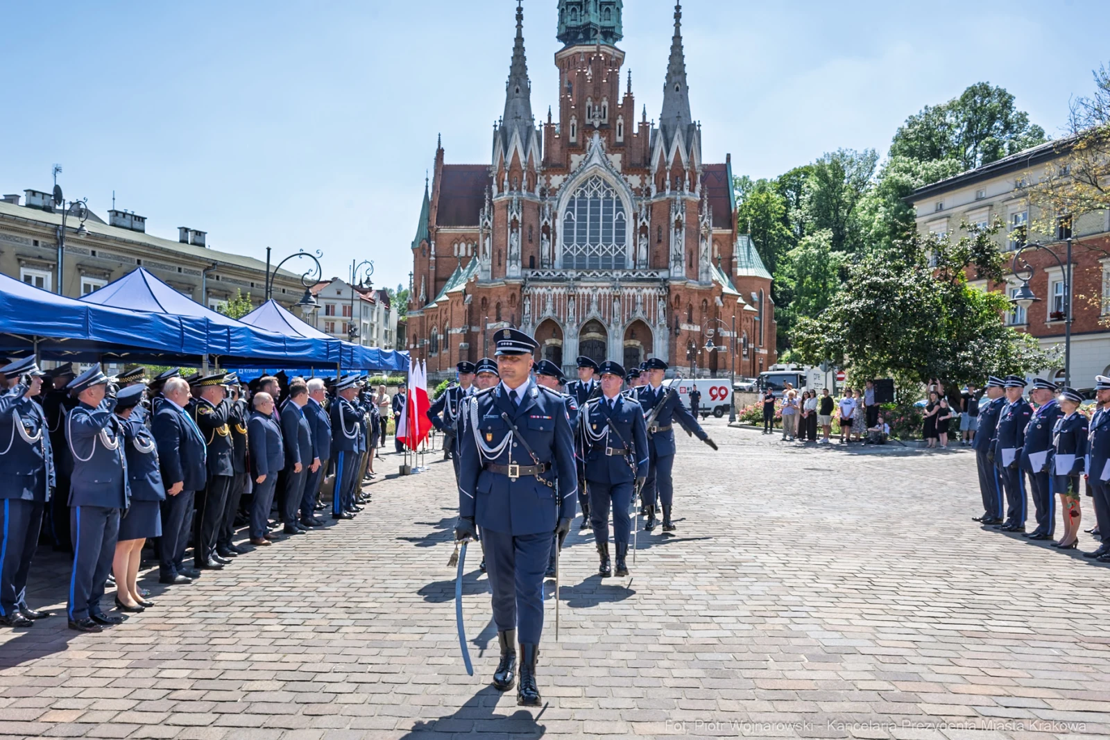 Uroczystość z udziałem policji przed zabytkowym budynkiem w słoneczny dzień.  Autor: Piotr Wojnarowski