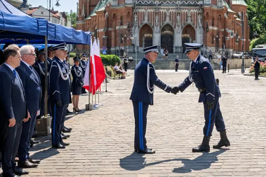 Ceremonia powitania z udziałem policjantów i przedstawicieli władz, w tle kościół.
