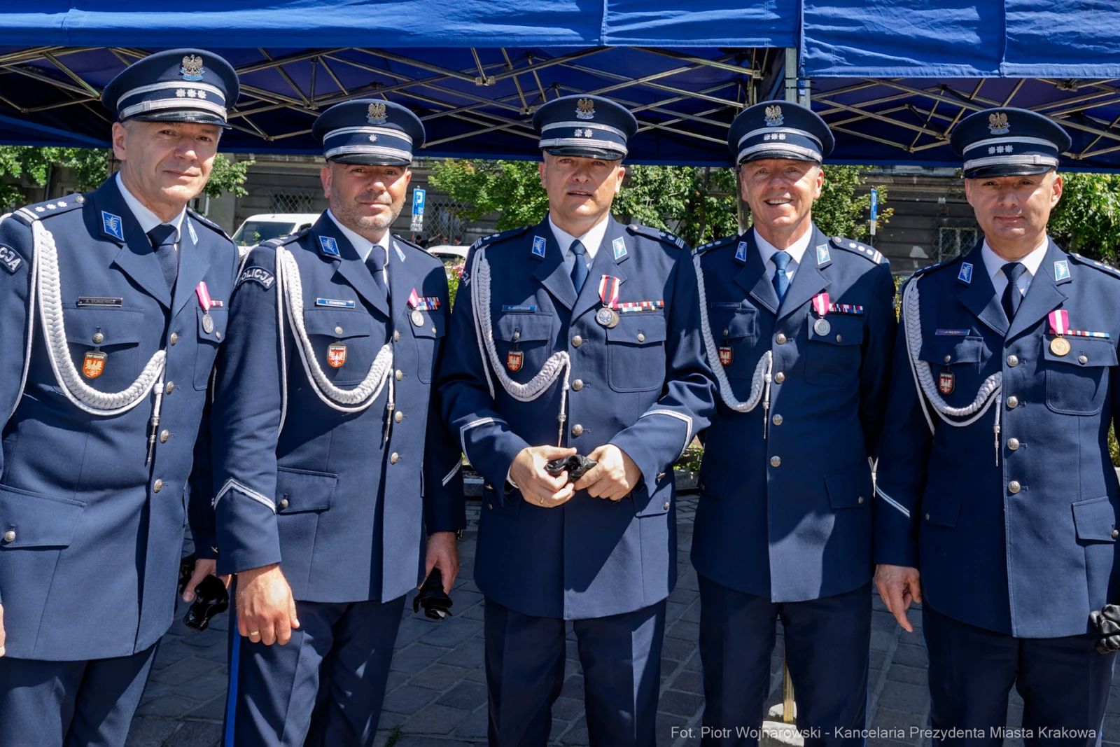 Grupa policjantów w mundurach, z odznaczeniami, na tle namiotu.  Autor: Piotr Wojnarowski