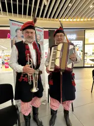 Dwaj muzycy w tradycyjnych strojach, jeden z trąbką, drugi z akordeonem.