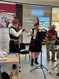 Trzech muzyków w tradycyjnych strojach gra na instrumentach w centrum handlowym.