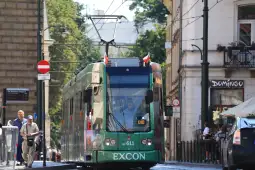 Tramwaj w mieście, przechodnie na ulicy, zielona reklama EXCON.
