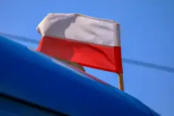 Flaga Polski na niebieskim tle.