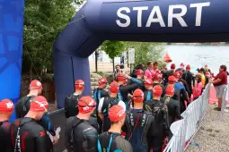 Zawodnicy w strojach triathlonowych czekają na start wyścigu.