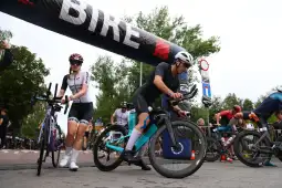 Zawodnicy przygotowujący się do wyścigu triathlonowego, rowery i baner z napisem BIRE.