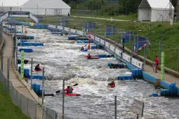 Zawodnicy kajakarstwa górskiego na sztucznej rzece, intensywne zmagania w wodzie.