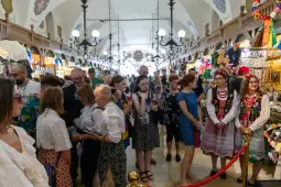 Tłum ludzi w tradycyjnych strojach, otoczeni straganami z pamiątkami.