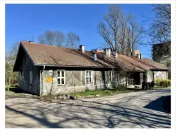Budynek mieszkalny z czerwonym dachem, otoczony drzewami i ścieżką.