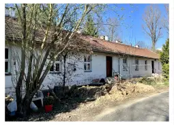 Budynek mieszkalny z ogrodem, widok zewnętrzny, drzewa w tle.