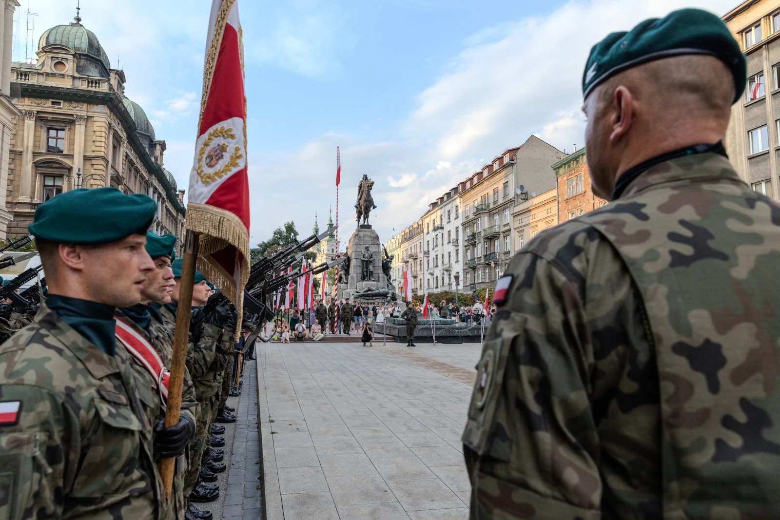 Żołnierze w mundurach wojskowych podczas ceremonii z pomnikiem w tle.  Autor: Bogusław Świerzowski