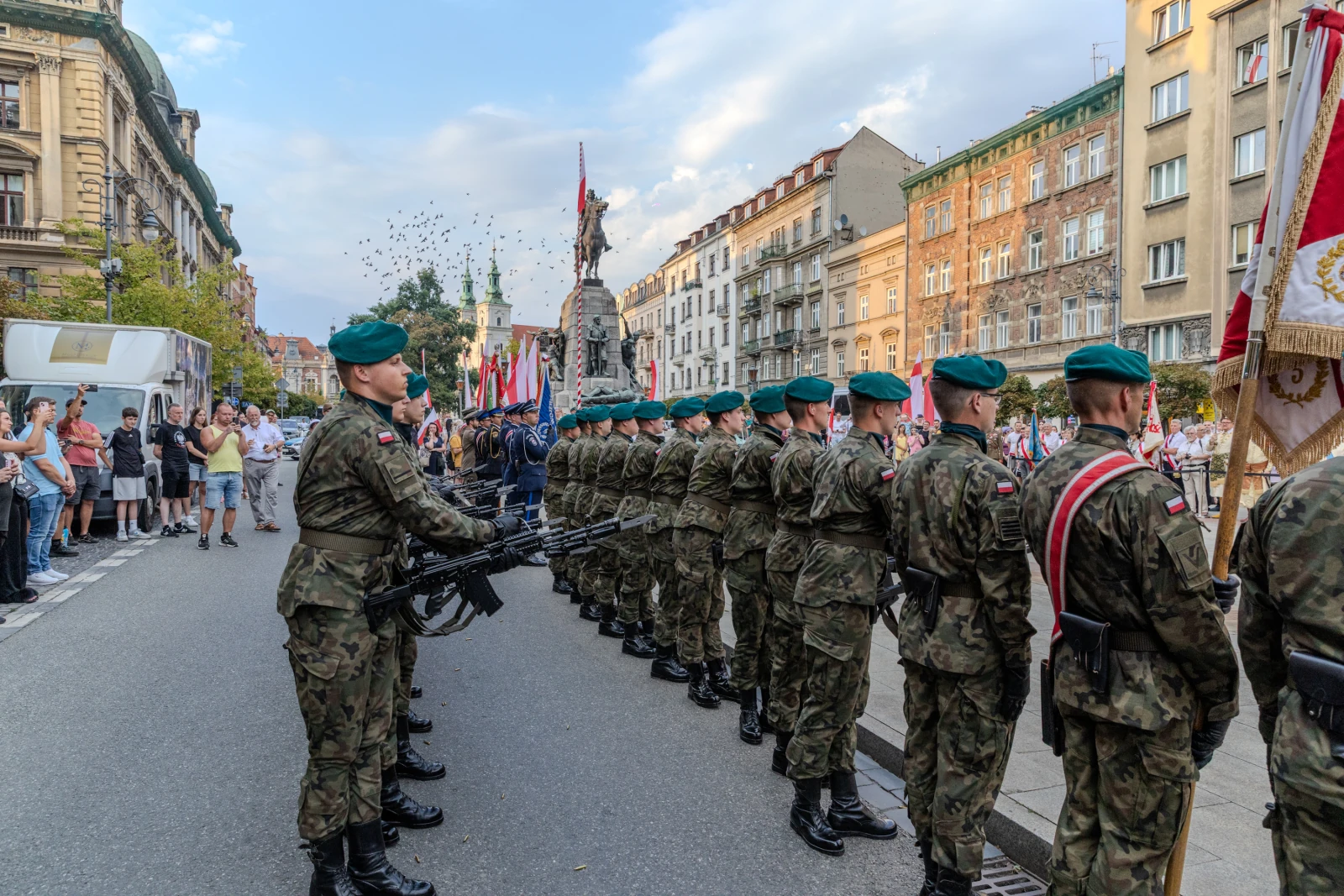 Żołnierze w mundurach z bronią, obok pomnika, podczas uroczystości z flagami.  Autor: Bogusław Świerzowski