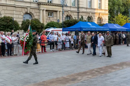 Ceremonia złożenia wieńca przez żołnierzy, uczestnicy w strojach narodowych i mundurach.