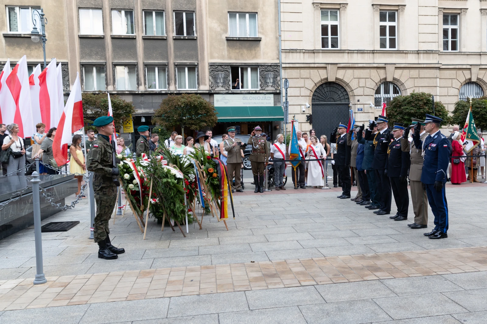 Uroczystość złożenia kwiatów przez żołnierzy i przedstawicieli władz w towarzystwie flag narodowych.  Autor: Bogusław Świerzowski