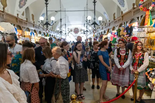 Tłum ludzi w tradycyjnych strojach, otoczonych straganami z pamiątkami.