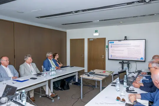 Spotkanie grupy ludzi w sali konferencyjnej z prezentacją na ekranie.