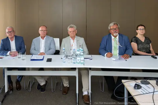 Grupa pięciu osób siedzących przy stole w sali konferencyjnej.