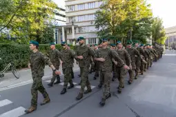 Żołnierze w mundurach maszerują w szyku na ulicy.