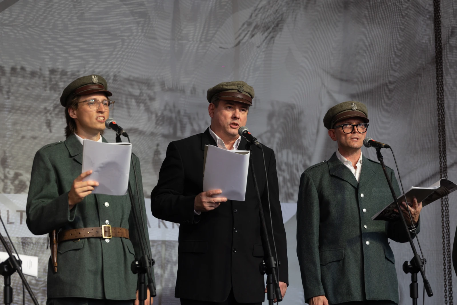Trzej mężczyźni w mundurach wojskowych recytują teksty na scenie.  Autor: Bogusław Świerzowski