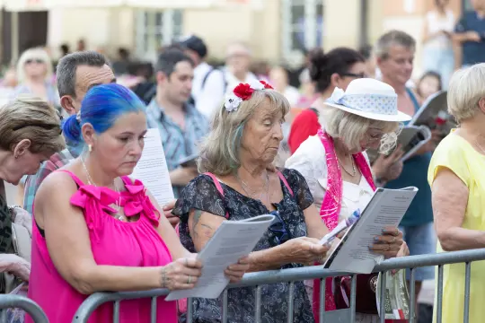Grupa osób z kartkami w rękach, uczestniczących w wydarzeniu na świeżym powietrzu.
