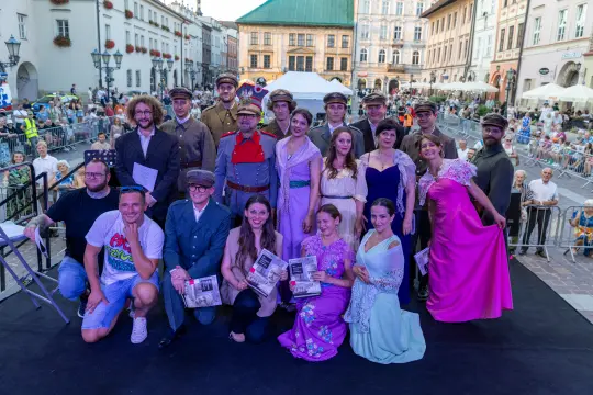 Grupa ludzi w strojach historycznych na tle miejskiego krajobrazu.