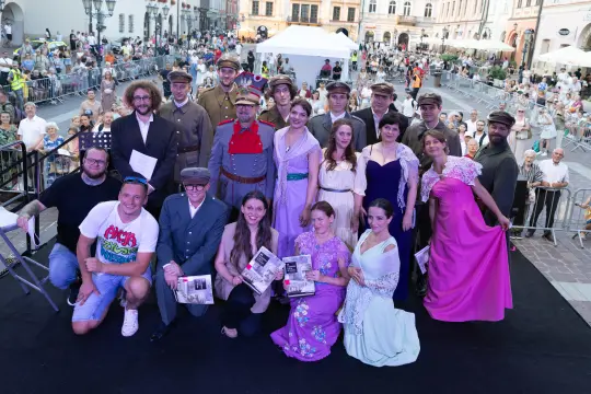 Grupa ludzi w strojach historycznych na tle tłumu podczas wydarzenia kulturalnego.