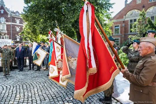 Uroczystość z udziałem żołnierzy i sztandarów w historycznej scenerii.