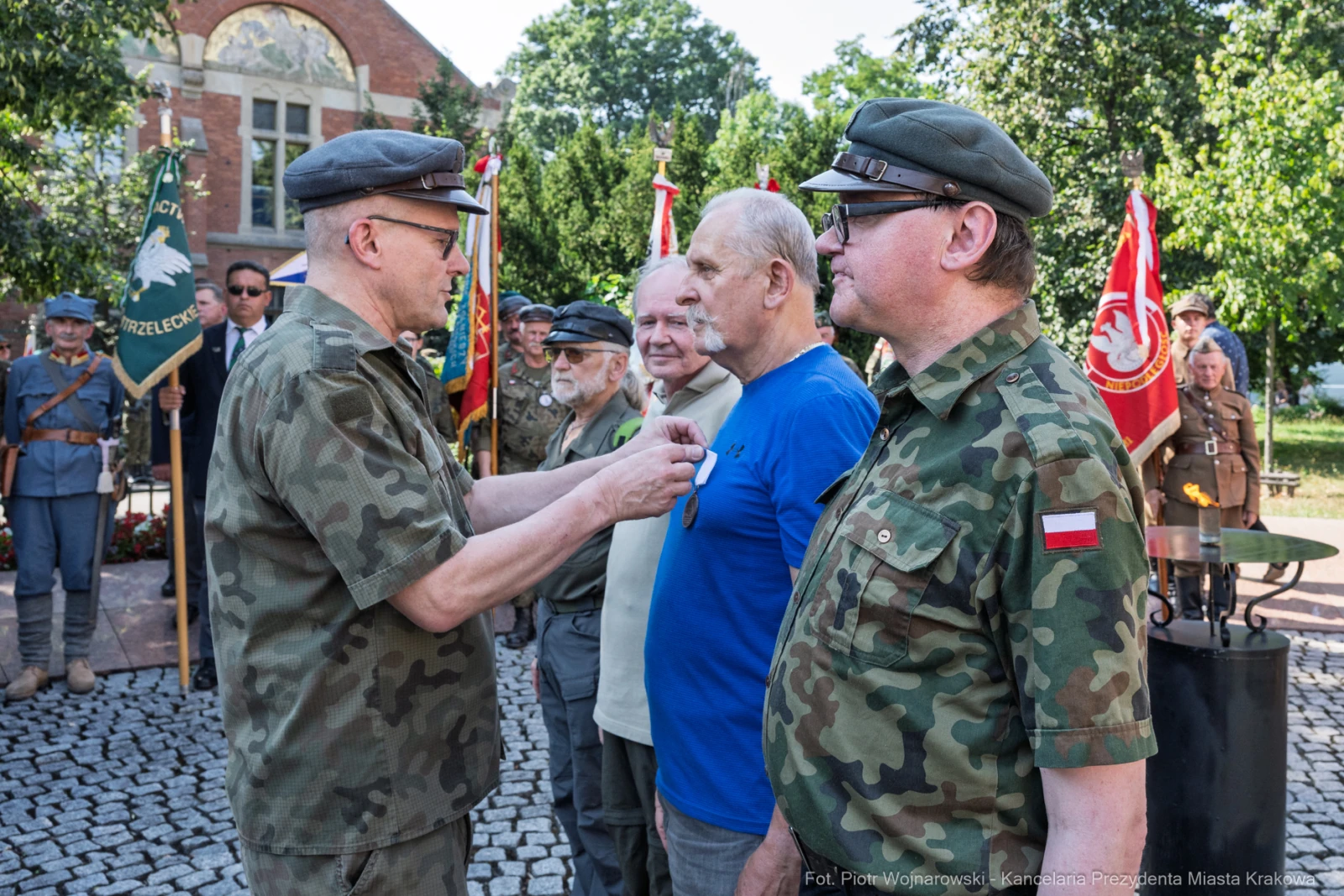 Wręczenie odznaczenia wojskowego mężczyźnie w niebieskiej koszulce podczas ceremonii.  Autor: Piotr Wojnarowski
