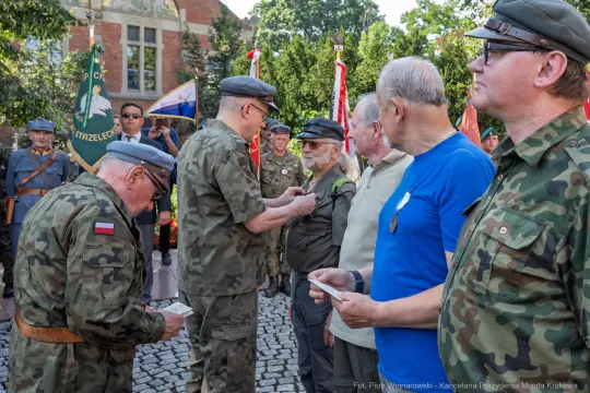 Ceremonia wręczenia odznaczeń weteranom, żołnierze w mundurach, flagi i medale.