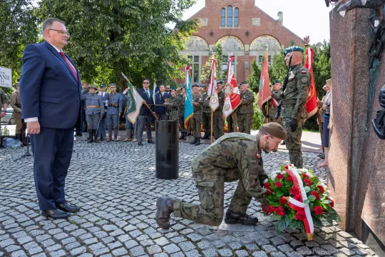 Uroczystość składania wieńca w hołdzie, obecność wojskowych i przedstawicieli władz.