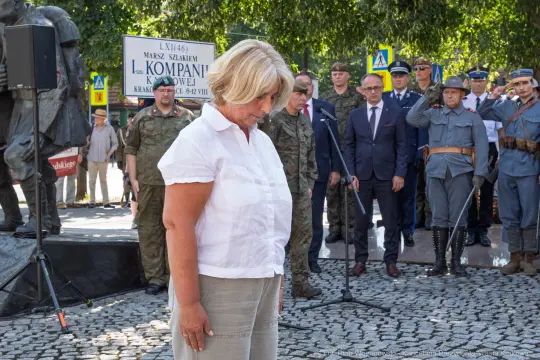 Kobieta składa hołd podczas uroczystości upamiętniającej żołnierzy. W tle zgromadzenie osób w mundurach.