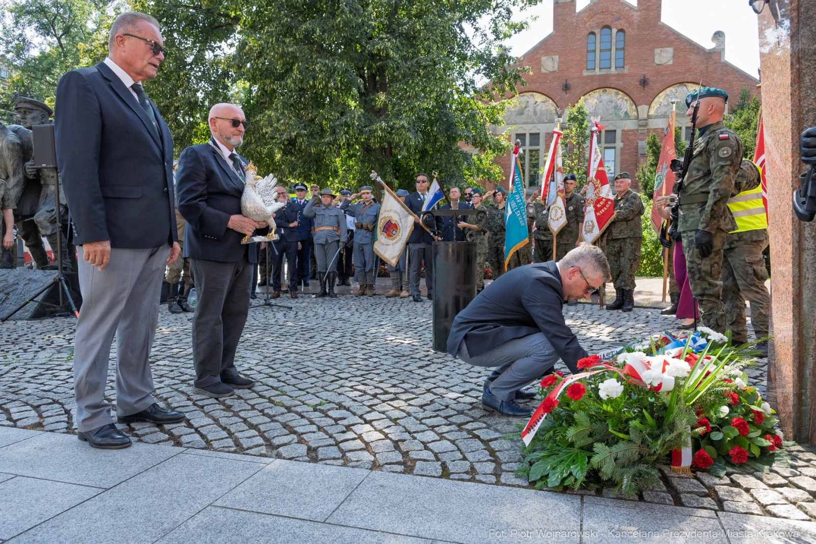 Uroczystość złożenia kwiatów przy pomniku, uczestnicy w mundurach i garniturach.  Autor: Piotr Wojnarowski