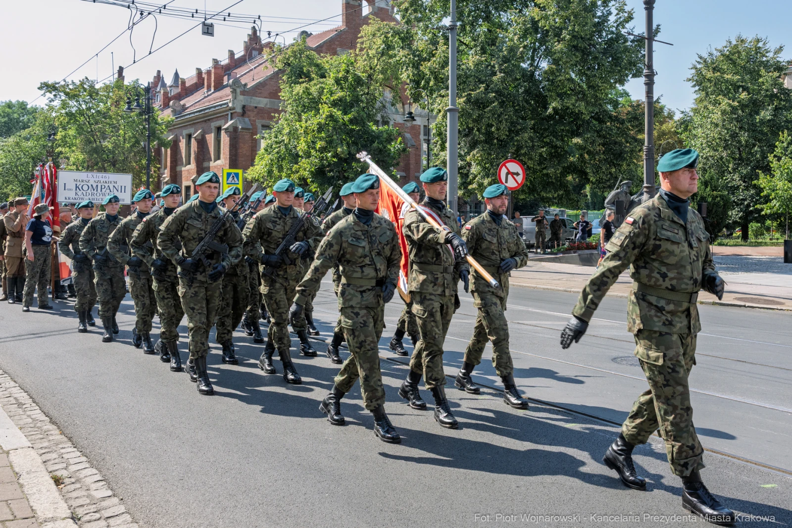 Żołnierze w mundurach wojskowych maszerują w defiladzie, trzymając flagi.  Autor: Piotr Wojnarowski