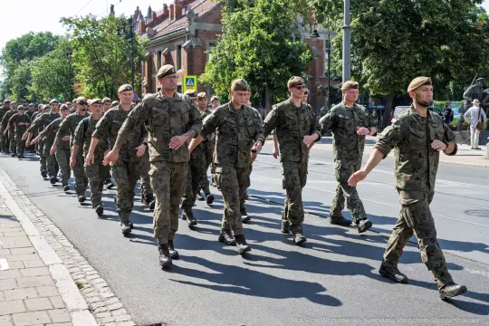 Żołnierze w mundurach maszerują ulicą podczas parady.